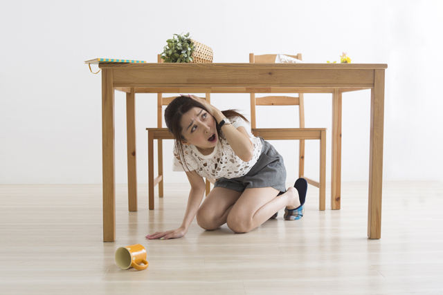 地震でテーブル下に避難する女性