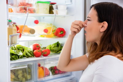 冷蔵庫の臭いに鼻をつまむ女性