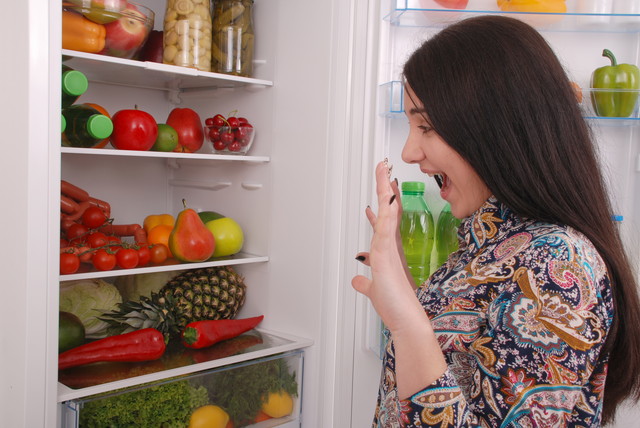 冷蔵庫の前でびっくりしている女性