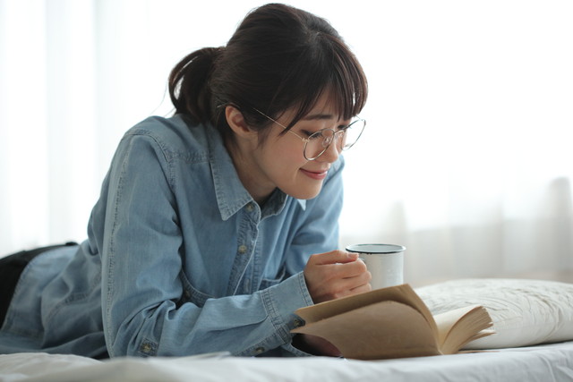 寝室で読書をする女性