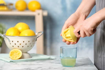 グラスにレモン汁を絞る女性