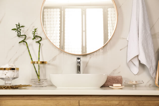 Stylish bathroom interior with vessel sink and round mirror