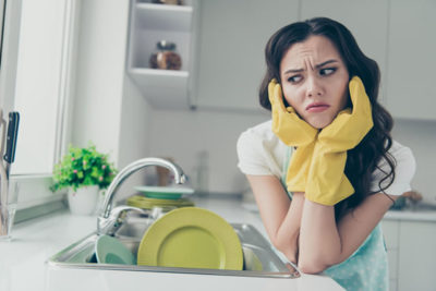 溜まった食器に嫌気が差している女性