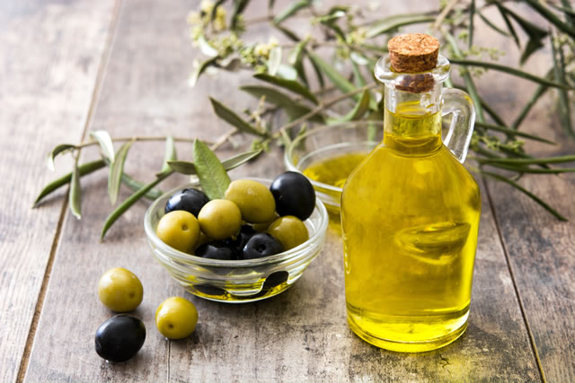 Virgin olive oil in a crystal bottle on wooden background