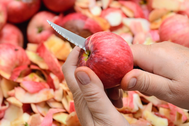 woman cuts red apples with a kitchen knife for jam. Concept - make jam, sweet. Work in the kitchen.