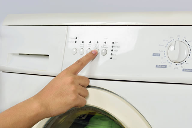 洗濯機のスイッチを押す指