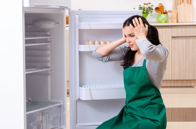 Young woman cleaning fridge in hygiene concept