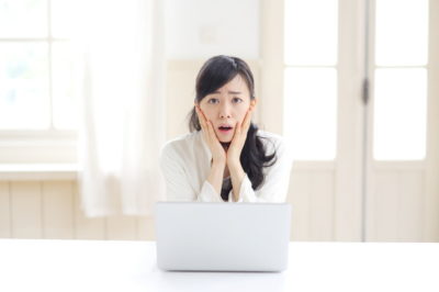 ノートパソコンの前で困った顔をしている女性