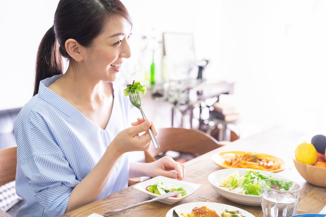 食卓で野菜サラダを食べる女性