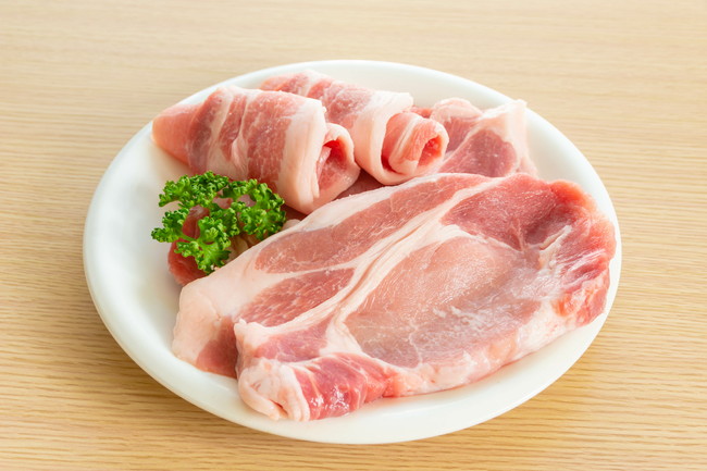 白い皿に置かれた生の豚肉肩ロース