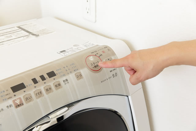 洗濯機のスイッチを押す指