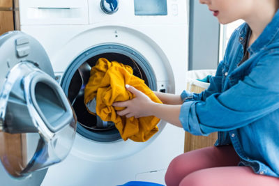 洗濯機に洗濯物を入れる女性