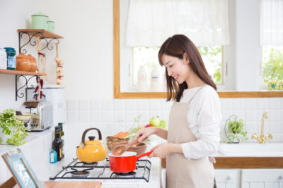 キッチンで赤い鍋を手にする女性