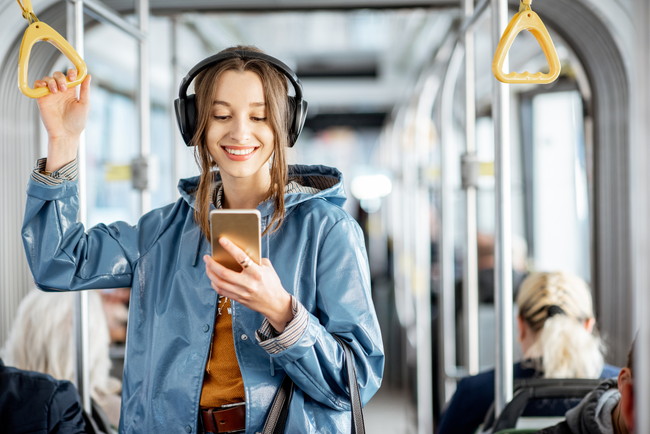 電車の中でヘッドフォンを付けて音楽を聴いている女性