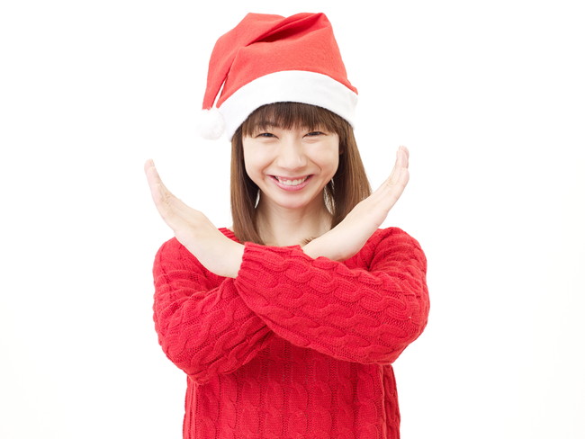 クリスマスの帽子をかぶりバツ印を示す女性