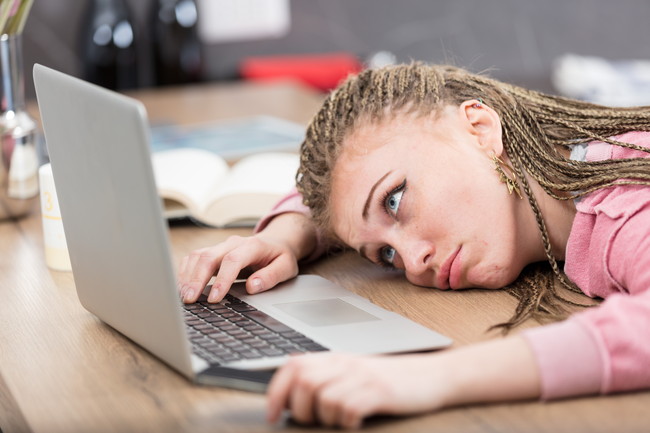 疲れ様子でパソコンを眺めている女性