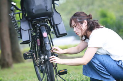 自転車が故障しているか確認している女性