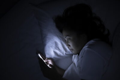 寝る前にベッドの中でスマホを見ている女性