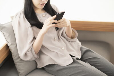 ソファでくつろぎながらスマホを操作している女性