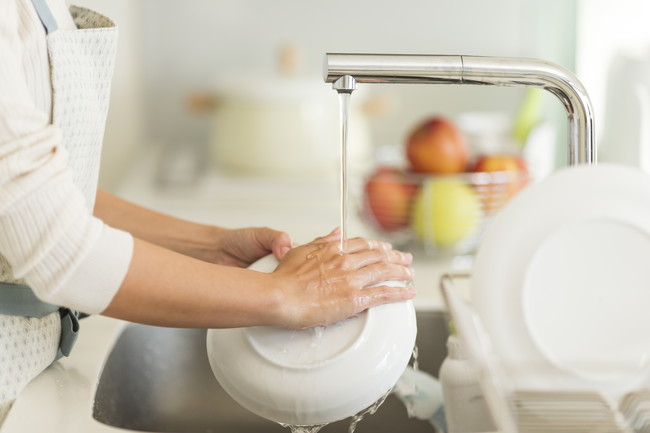 キッチンで食器洗いをしている女性
