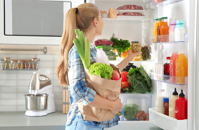 冷蔵庫に食品を入れている女性