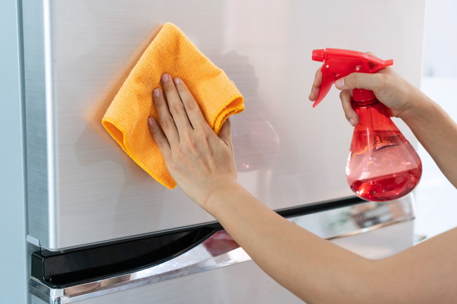 洗剤とタオルで冷蔵庫の扉を掃除をしているところ