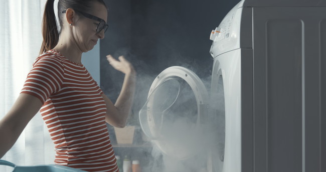 煙の出ている洗濯機と女性