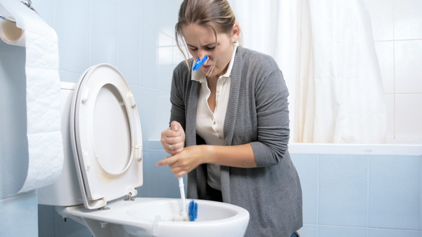 トイレ掃除で悪臭を取り除こうとしている女性