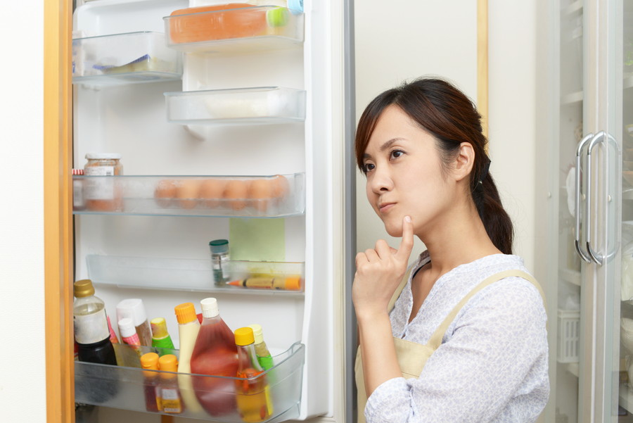 冷蔵庫を開けて考え事をする主婦