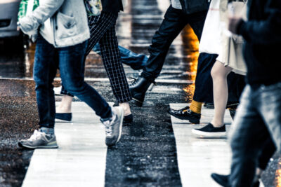 雨が降る中横断歩道を歩いている人々