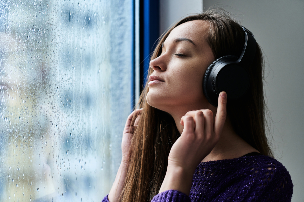 雨が降る日に部屋の中で音楽を聴いている女性