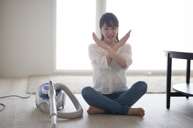掃除機を横に置いた女性
