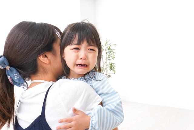 泣いている子供を抱っこする母親