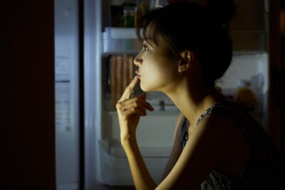 深夜に冷蔵庫をのぞく若い女性