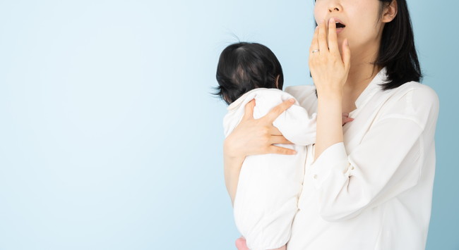 赤ちゃんを抱えあくびをしている母親