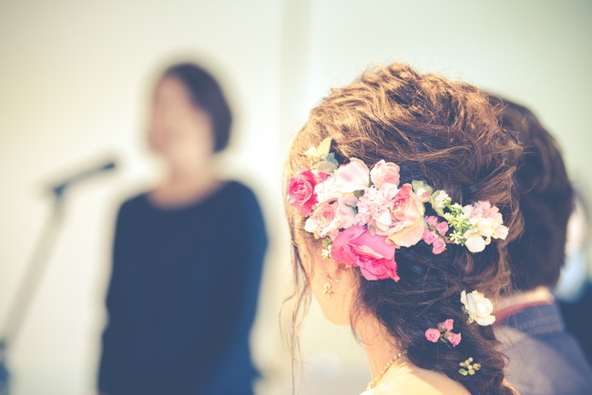 結婚式でスピーチをしている女性と花嫁の後ろ姿