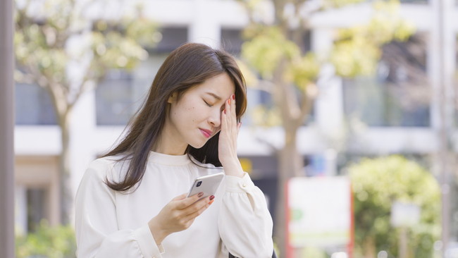 スマホを持って考えている女性