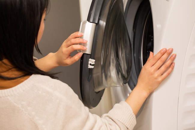 ドラム式洗濯機で洗濯をする女性