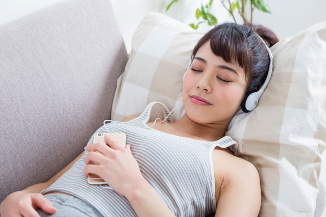 ソファーで音楽を聴く女性