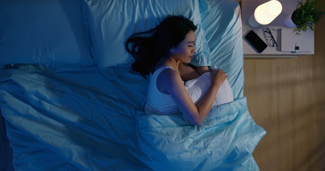 ベッドで横向きで眠る女性