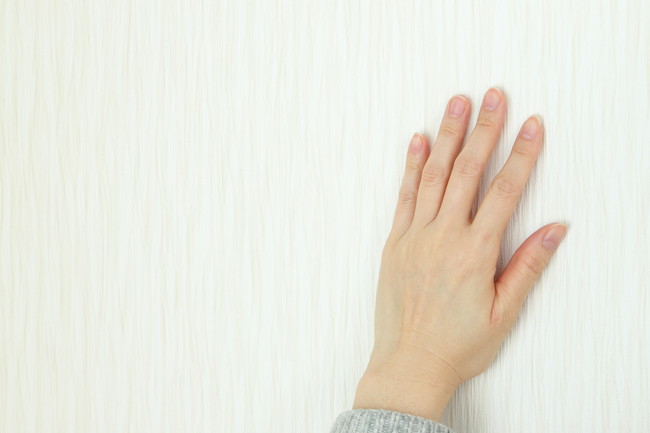 白い壁に触れる手