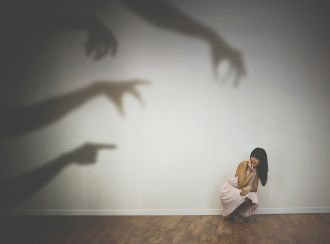 壁に映る人の手の影と怯える女性