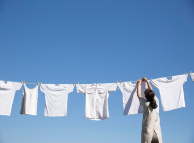 青空の下で洗濯物を干す女性