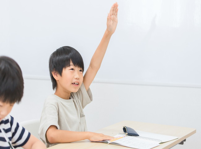授業中に挙手をする少年