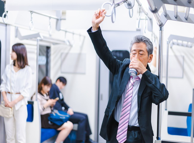 電車の中でお酒を飲む酔った男性