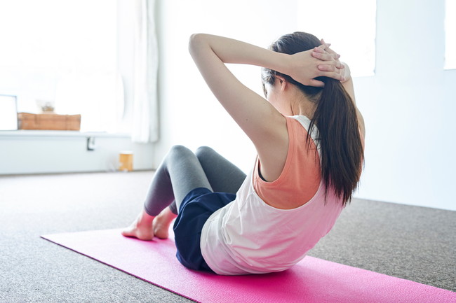 部屋の中でトレーニングをする若い日本人の女性