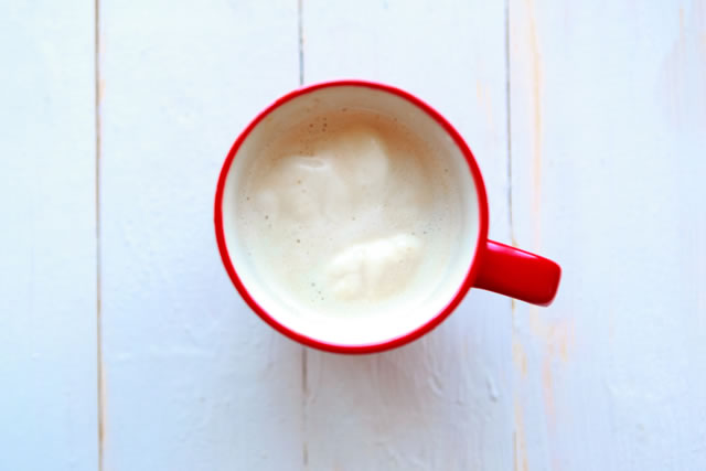 Coffee cup with milk on white wooden background.