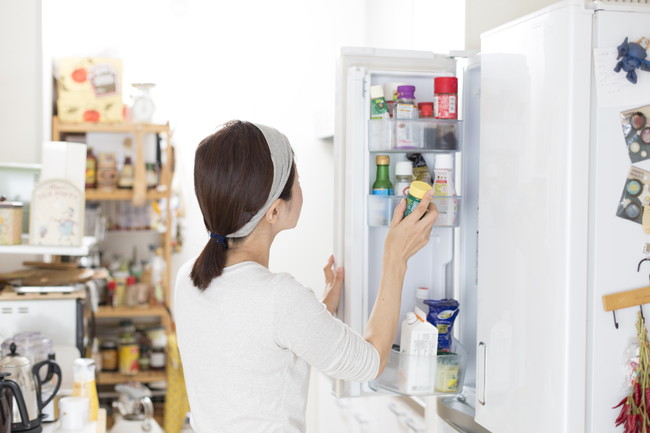 冷蔵庫を開けて調味料を取り出している女性