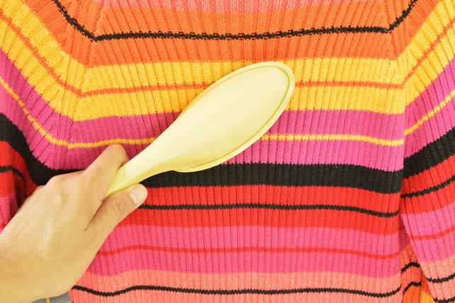 sticky brush in hand cleaning hair and dust on colorful sweater