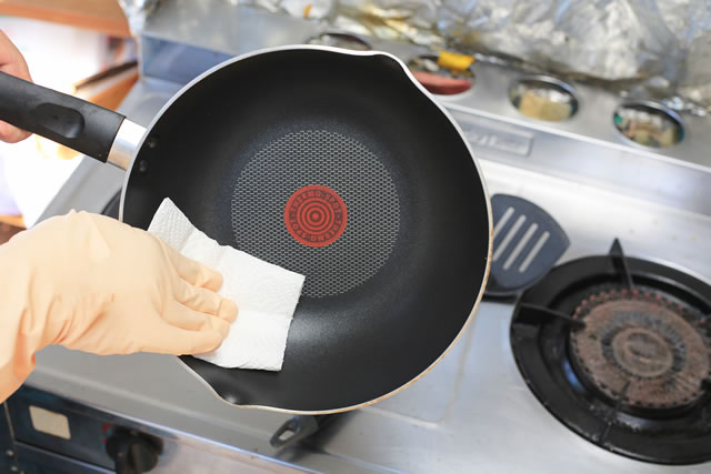 Cropped image of woman washing frying pan in kitchen.